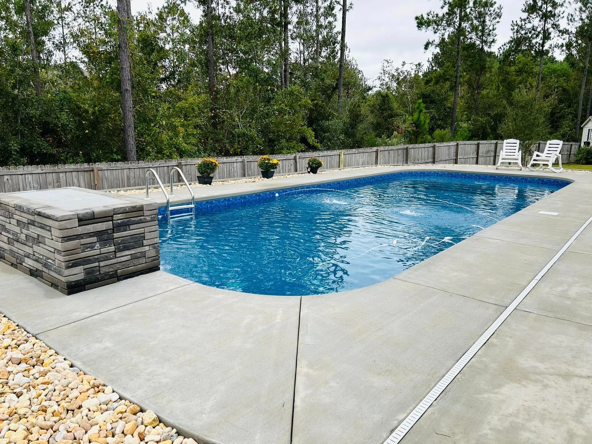 A large swimming pool is surrounded by rocks and trees.