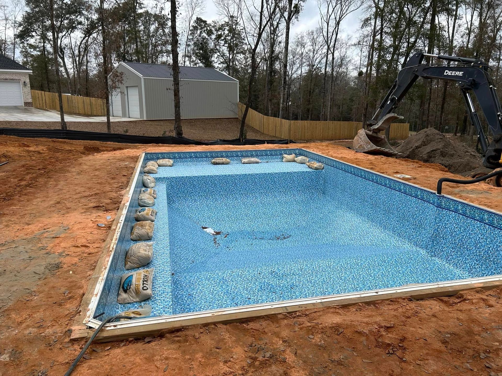 A swimming pool is being built in the backyard of a house.