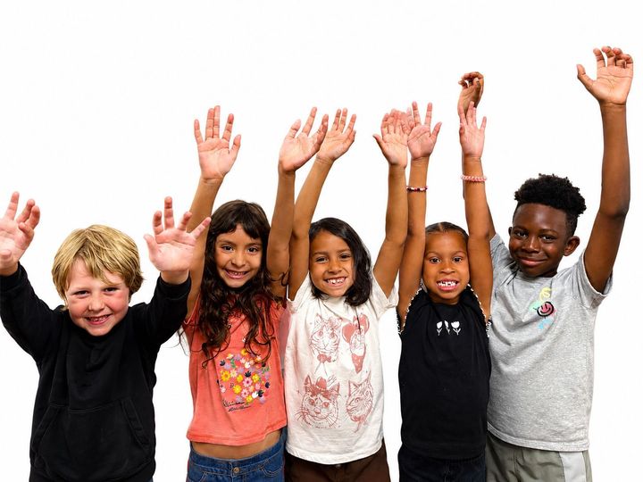 A group of children with backpacks are raising their hands in the air. A group of children with backpacks are raising their hands in the air.