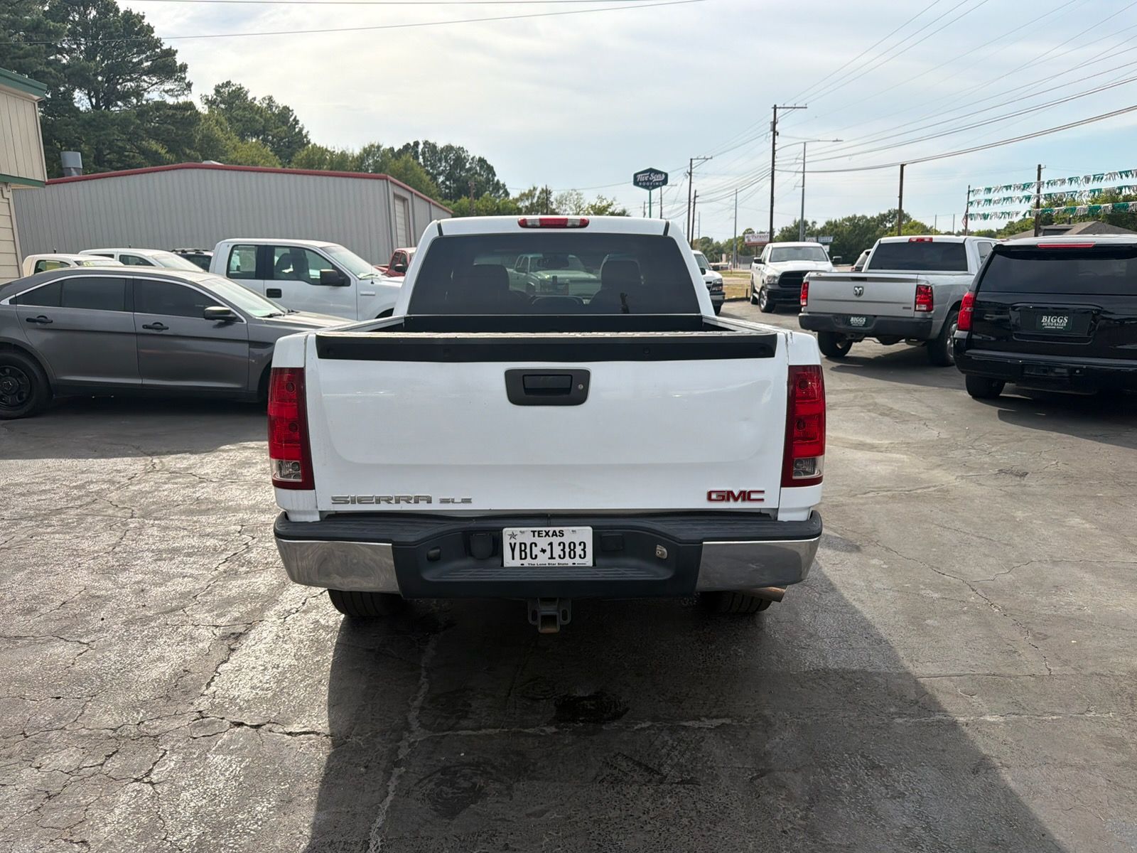 White GMC pickup truck seen from the rear in a parking lot on a sunny day