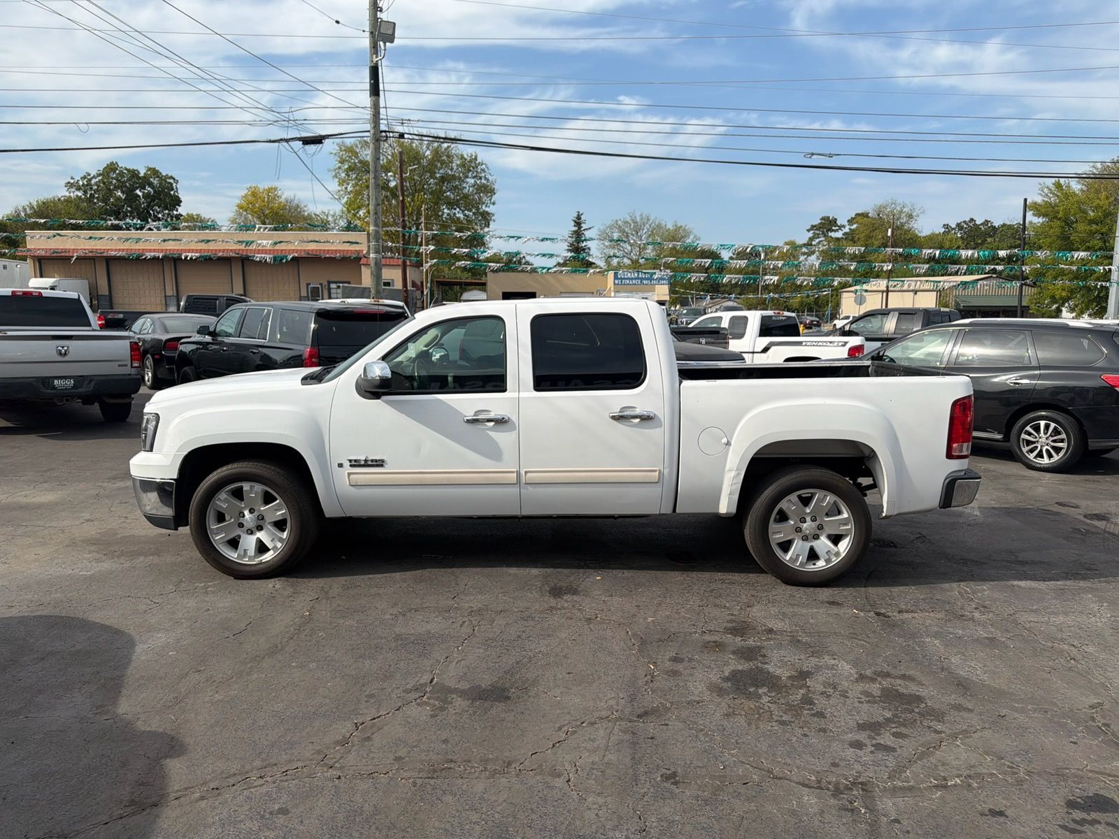 White pickup truck parked in a lot with other cars under a cloudy sky