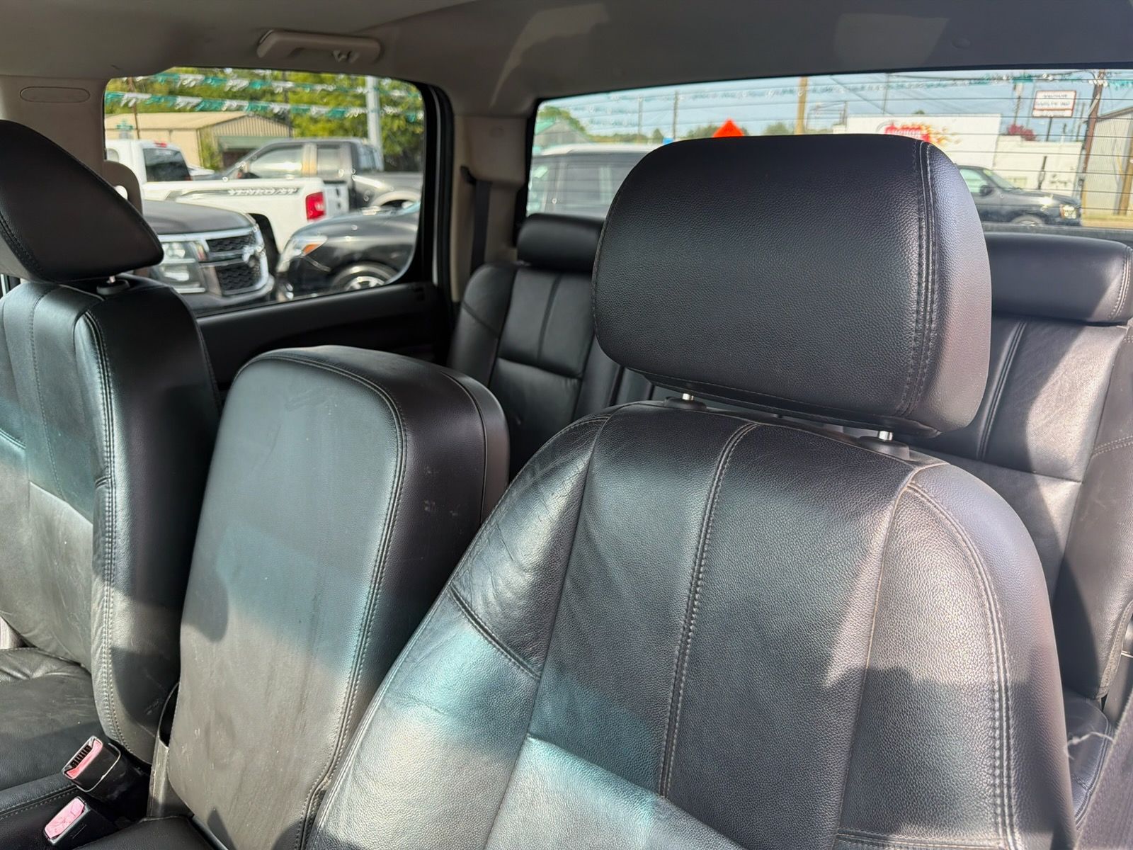 Car interior with black leather seats and a steering wheel, viewed from the back seat.