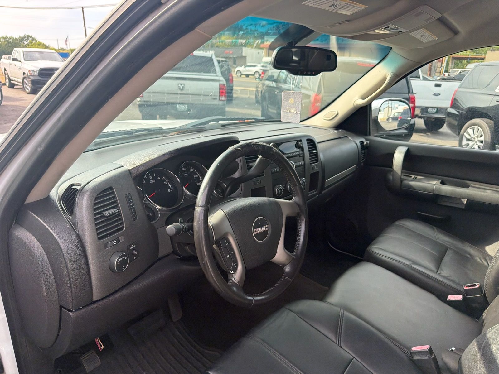 Black leather car interior viewed from open driver’s door, showing dashboard, steering wheel, and front seats