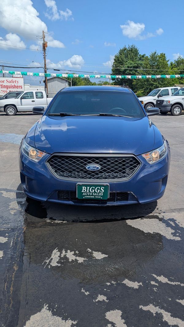 Blue Ford Taurus car parked outside, with dealership sign visible.