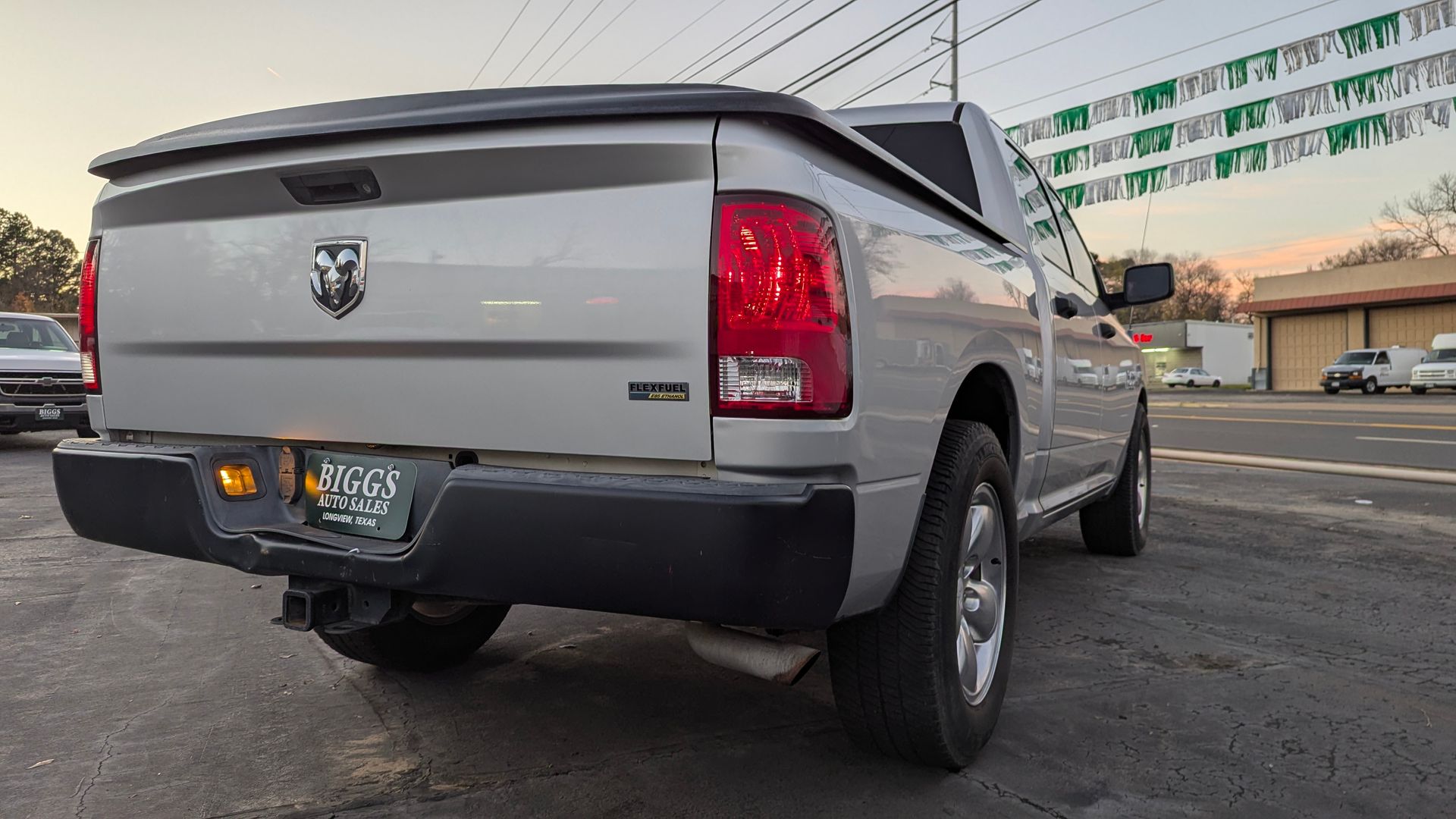 Silver Dodge Ram pickup truck parked near a building, with a license plate.