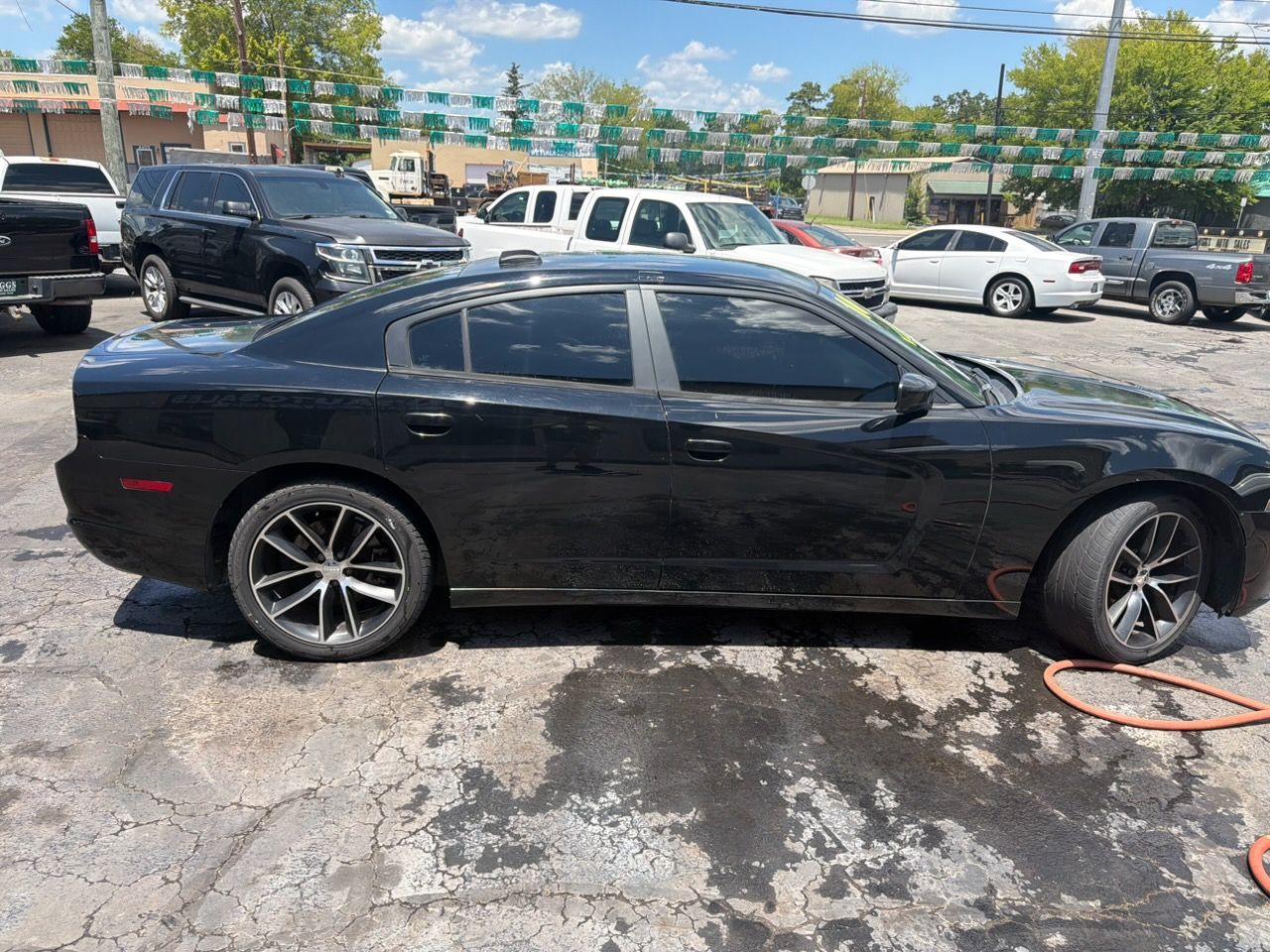 Black coupe in a parking lot with a tow strap attached to the front wheel
