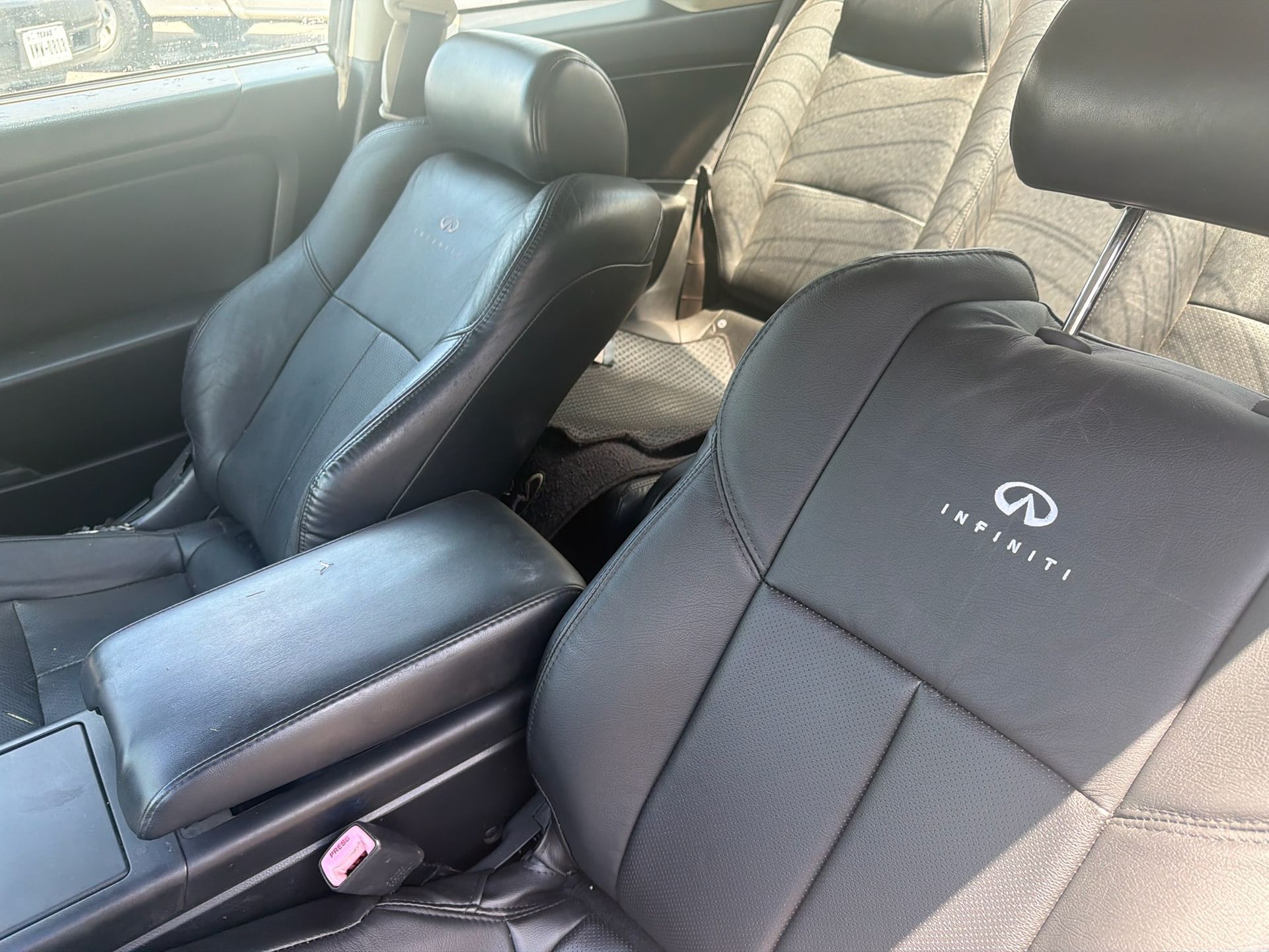 Interior of an Infiniti car with black leather front seats and silver seat covers in the back seat.