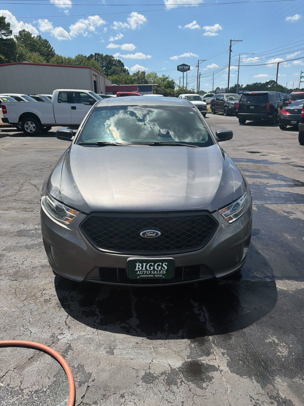 Silver Ford SUV parked on a wet car lot under a partly cloudy sky