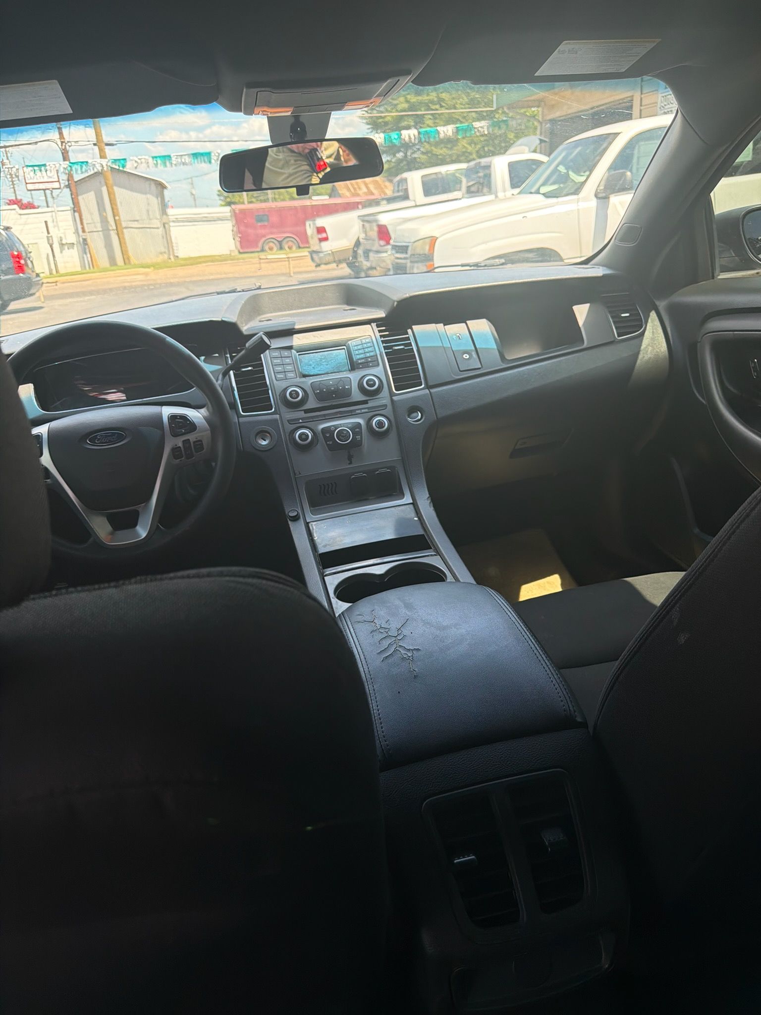 Car interior with steering wheel, center console, and dashboard, viewed from the back seat.