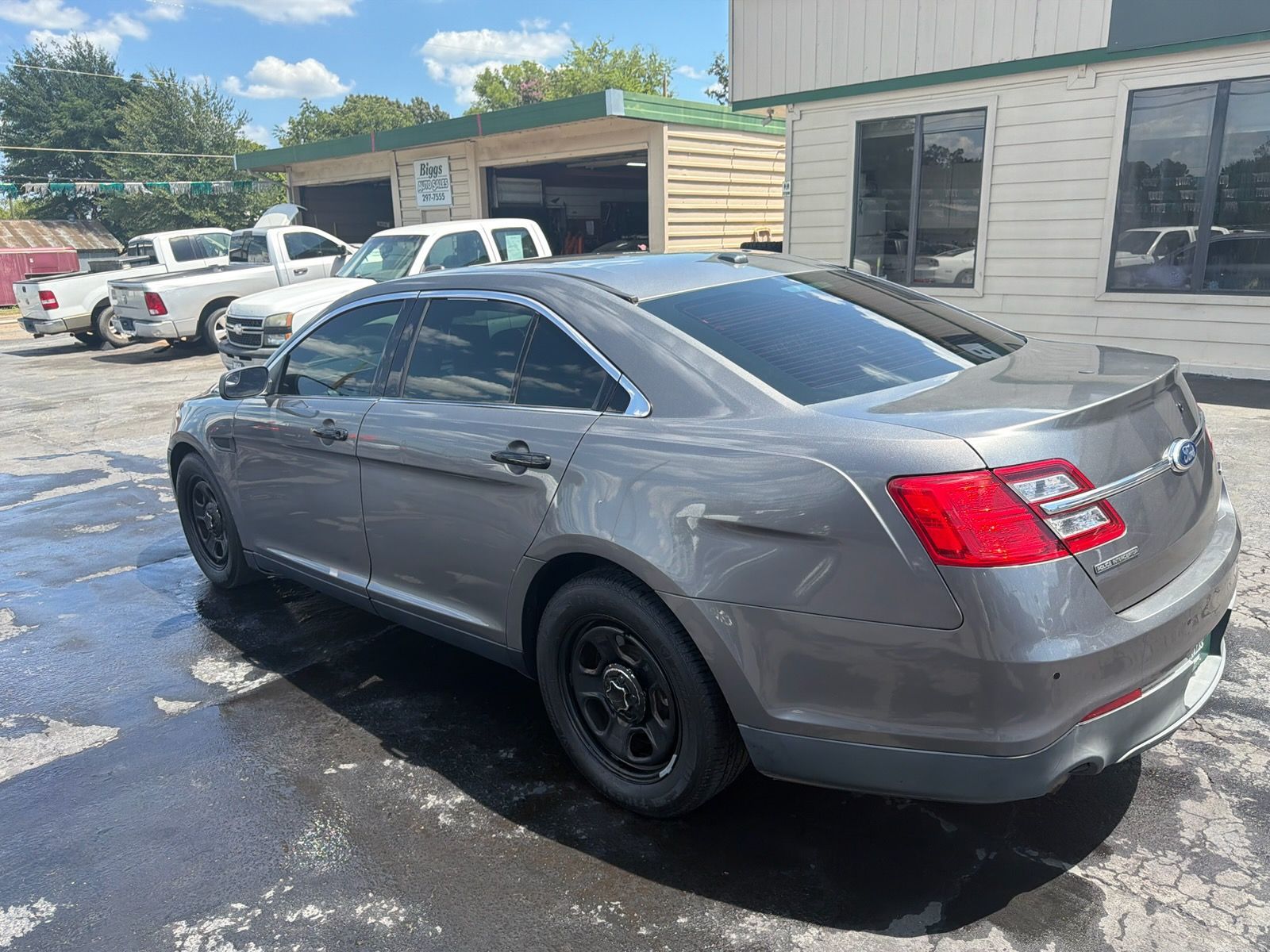 Silver sedan parked outside an auto shop on a wet lot