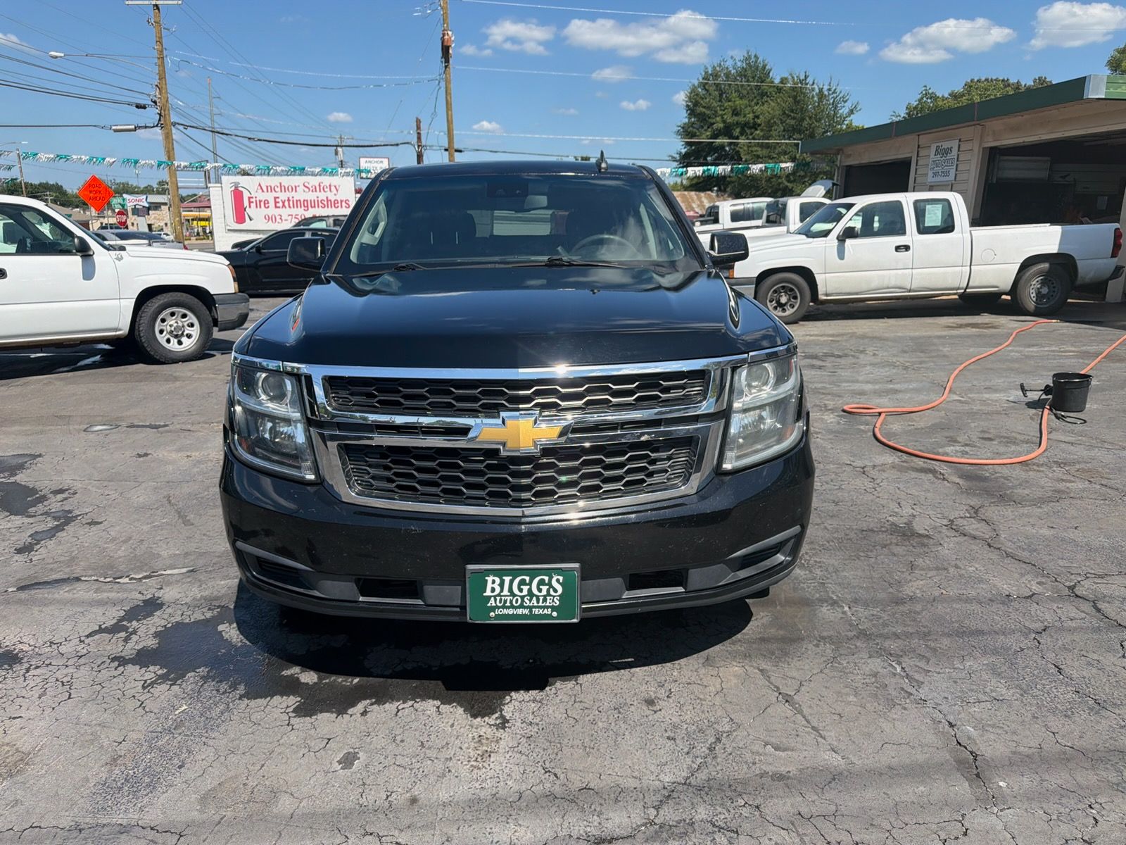 Front view of a black Chevrolet SUV parked on a car lot with other vehicles nearby.