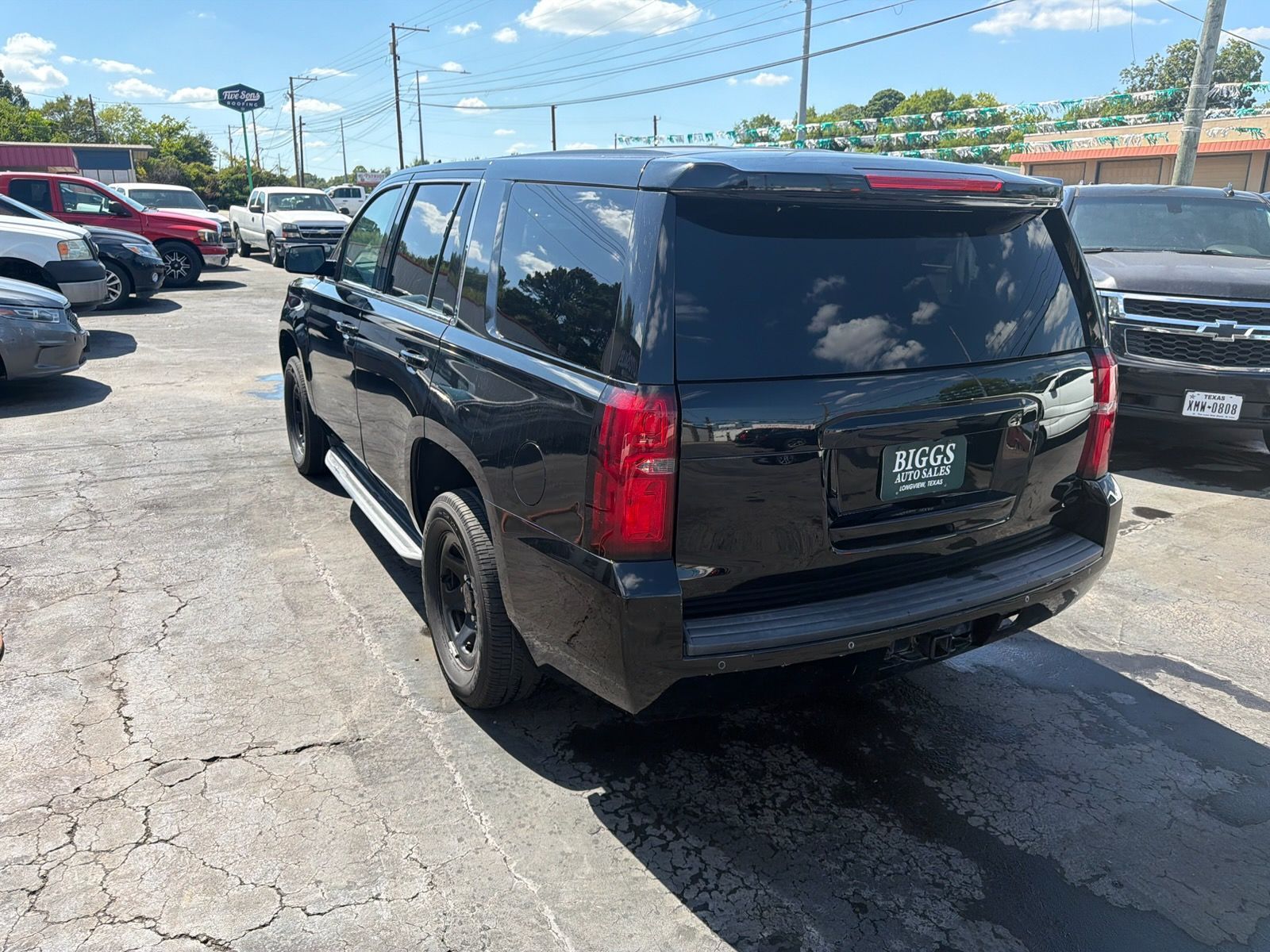 Black SUV parked in a sunny parking lot, rear three-quarter view