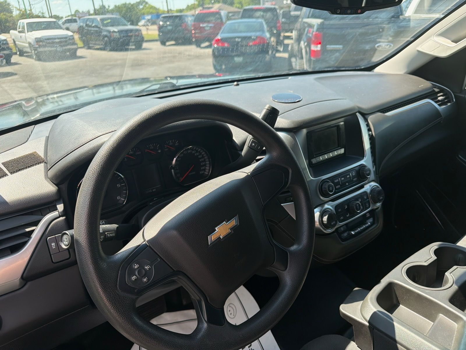 Chevrolet truck dashboard and steering wheel, with parking lot visible through the windshield