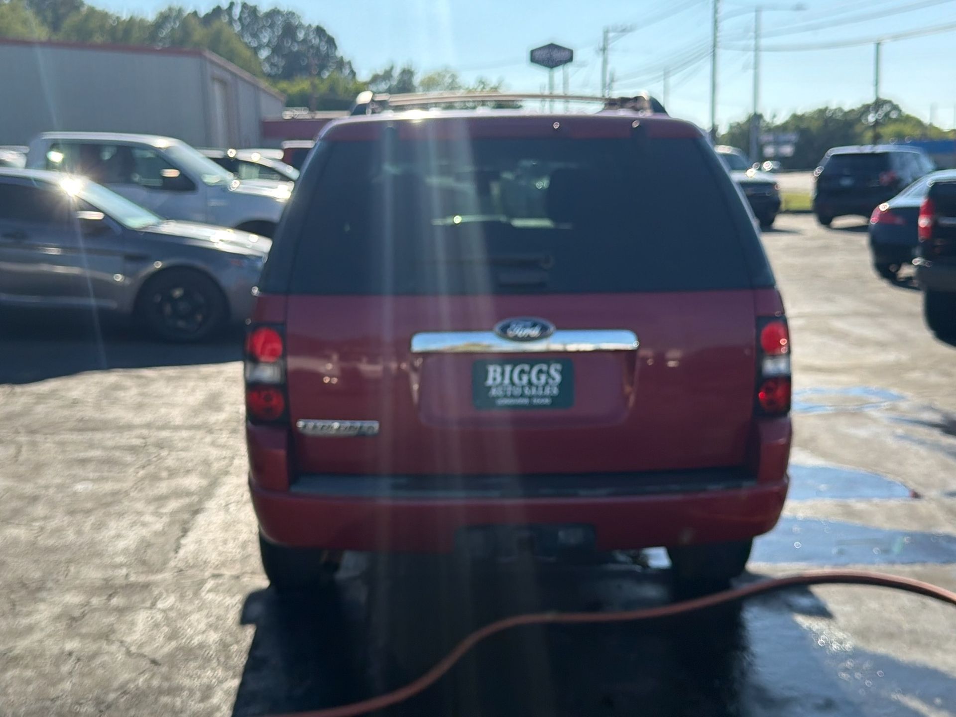 Rear view of a red Ford SUV parked in a lot with a BIGGS plate frame.