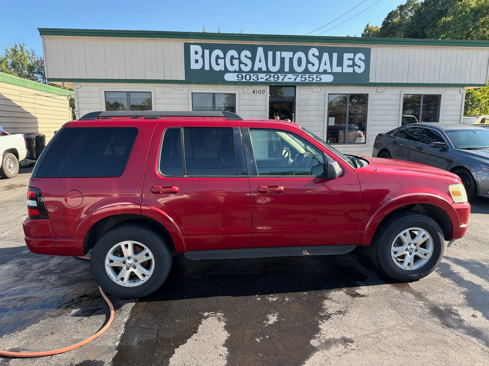 Red SUV parked outside Biggs Auto Sales dealership on a wet lot