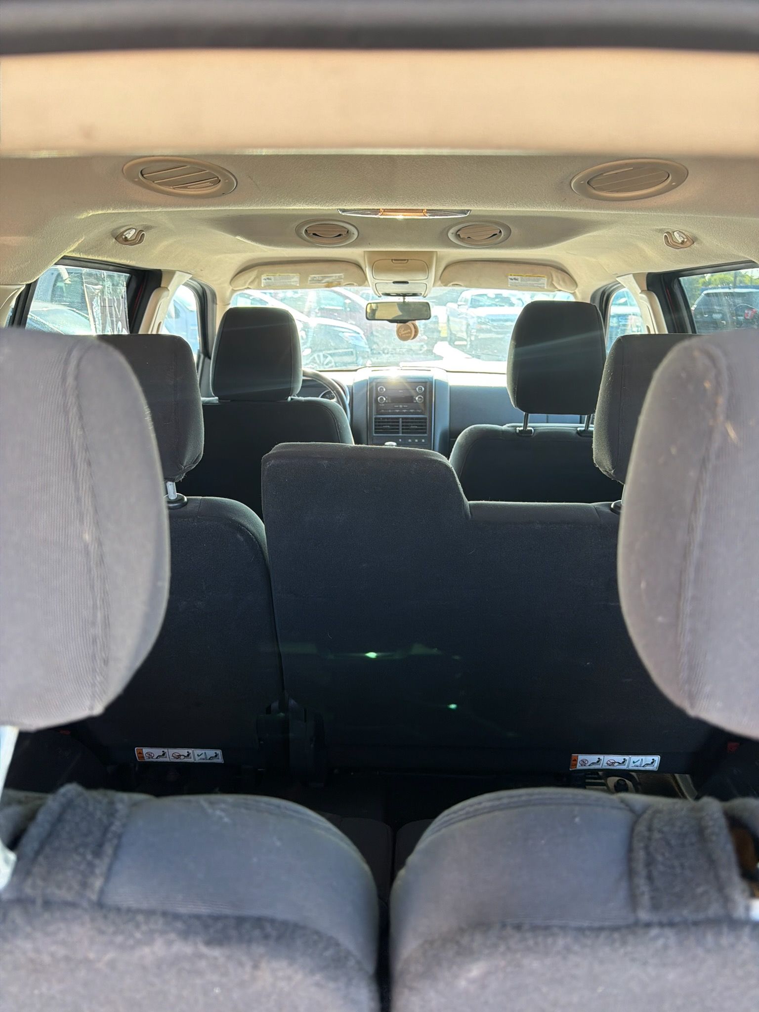 Interior view of a van with gray seats and open sight through the windshield to a bright outside scene