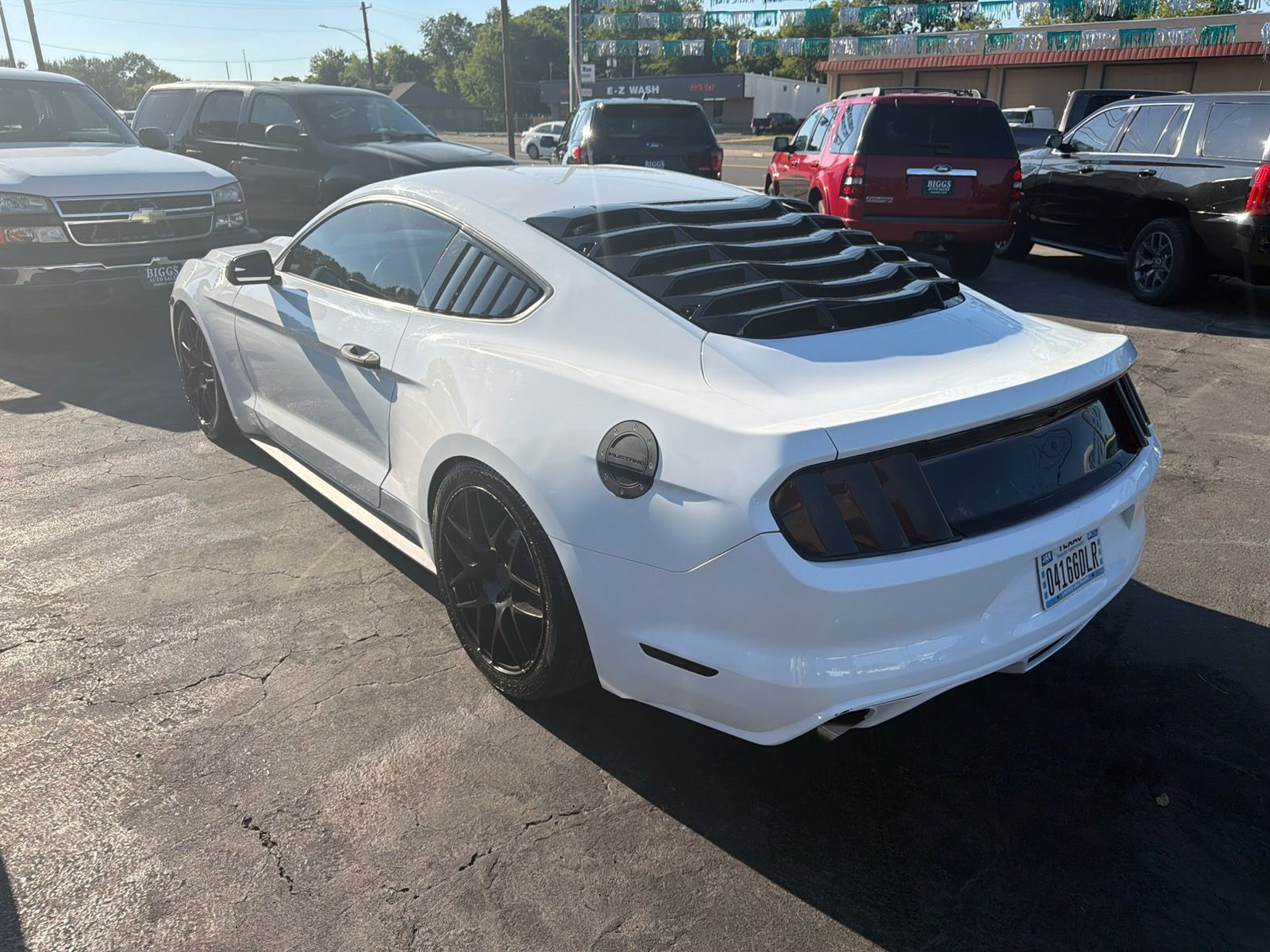 White sports car with black rear louvers parked in a lot on a sunny day