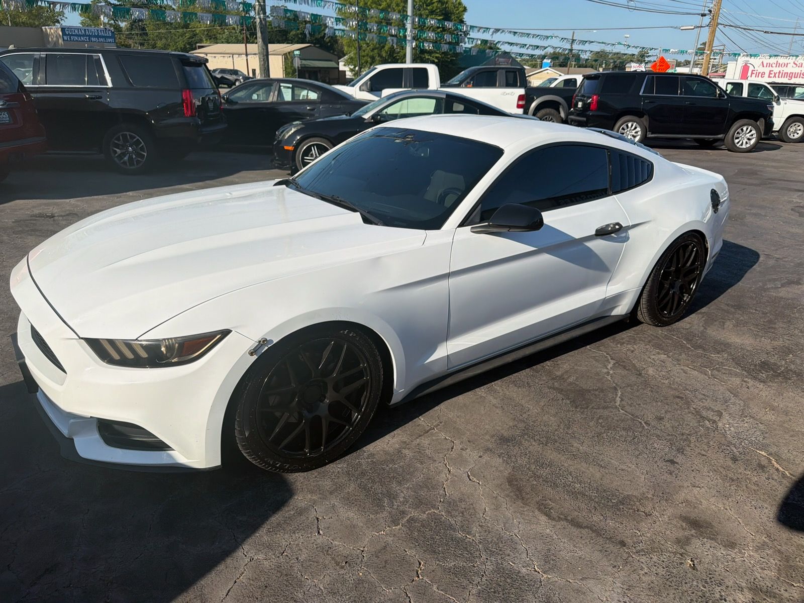 White sports car parked in a lot, angled front-left view, with black wheels and tinted windows.