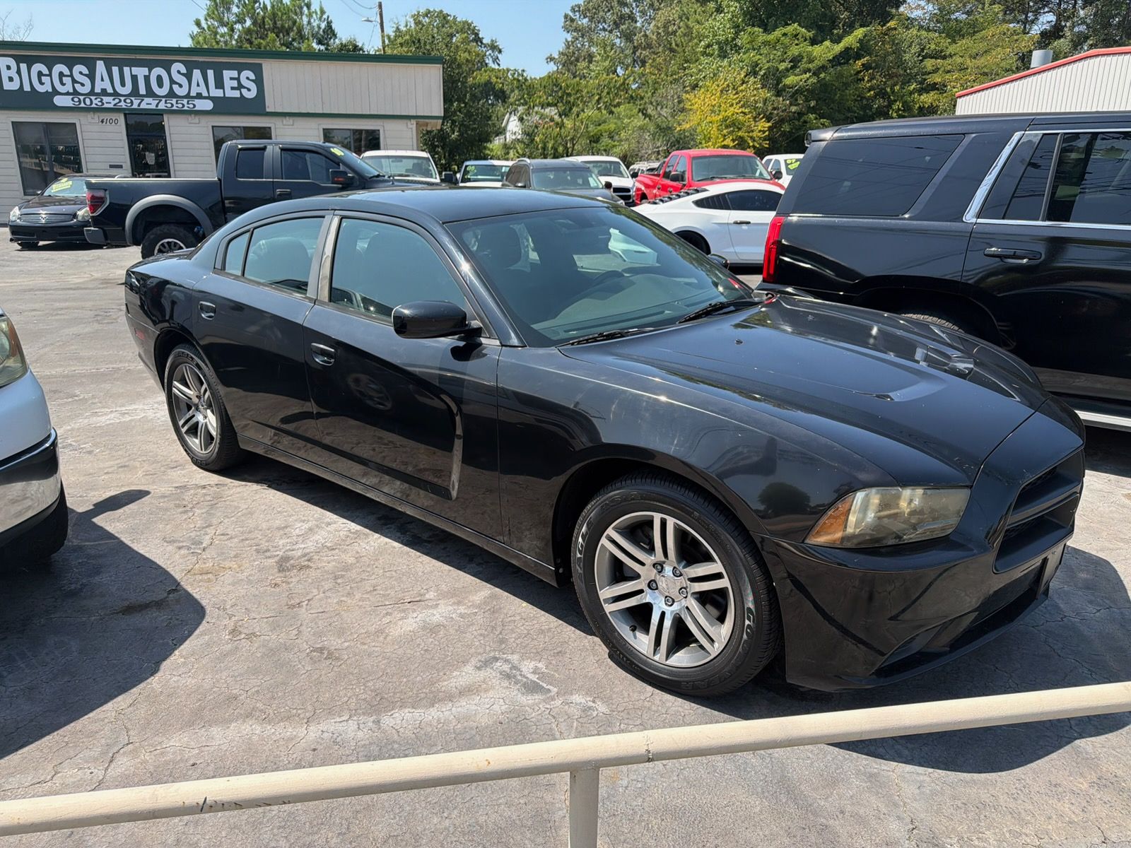 Black sedan parked at a used car lot with other vehicles and a Bigg's Auto Sales sign in the background