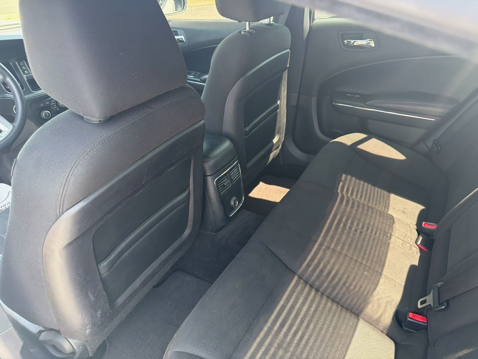 Rear car seat interior with gray fabric seats and sunlight on the bench seat.
