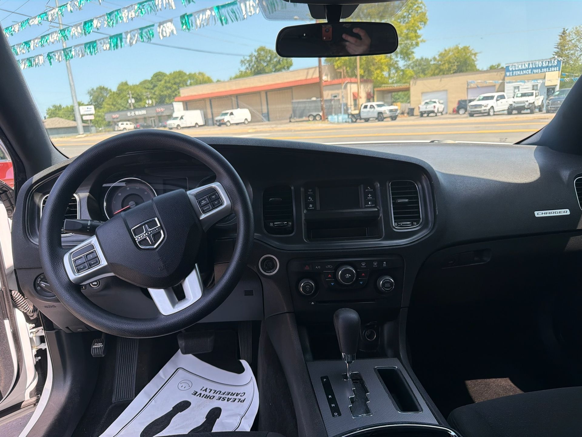 Inside a car, showing the dashboard, steering wheel, and center console from the driver’s seat.