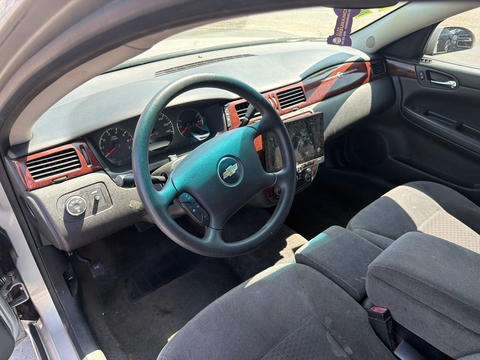 Car interior with black seats, steering wheel, dashboard, and red trim in daylight