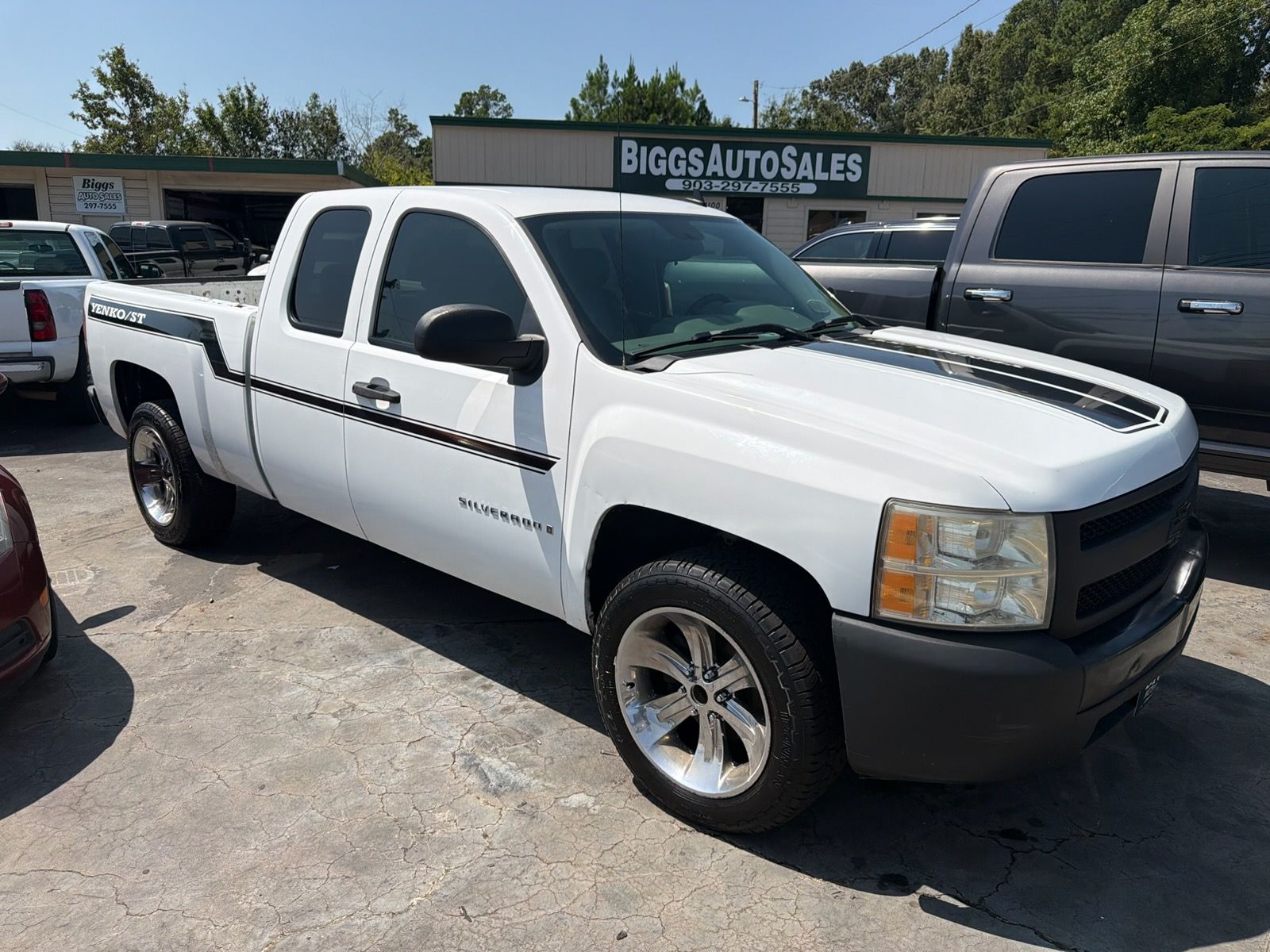 White pickup truck parked on a sunny lot in front of a store sign, side view