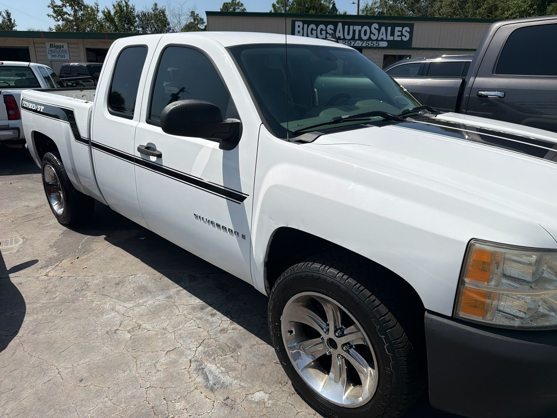 White pickup truck parked at a car lot with a Bigos Auto Sales sign in the background