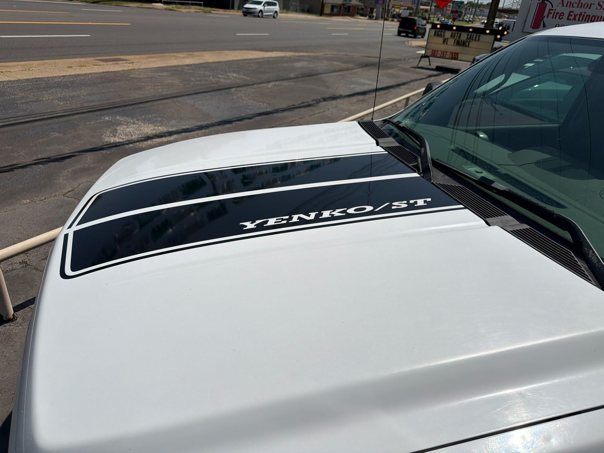 White truck hood with black “VENOM” decal parked by a roadside repair area