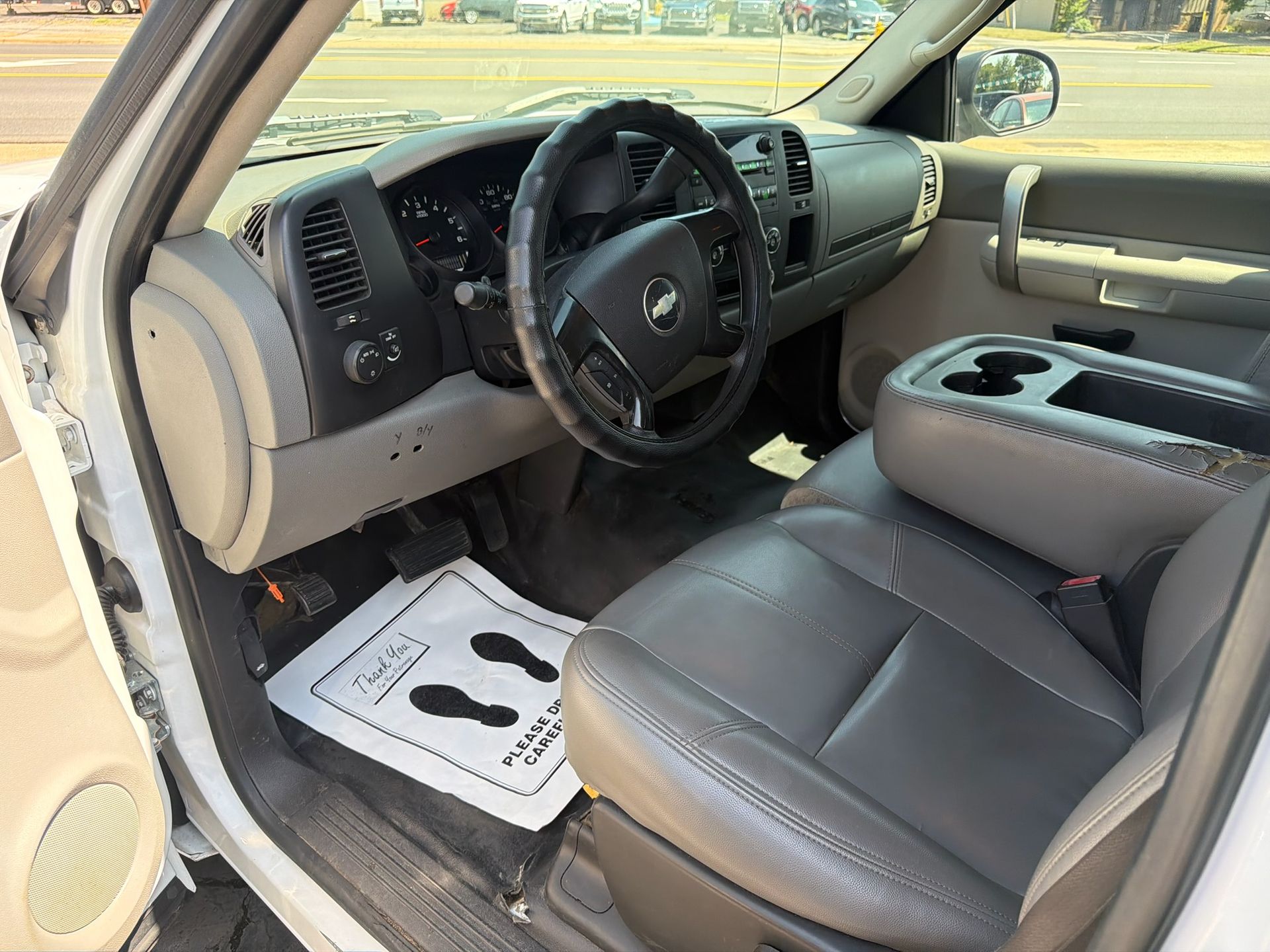 Interior of a beige car, showing the driver’s seat, steering wheel, and center console.