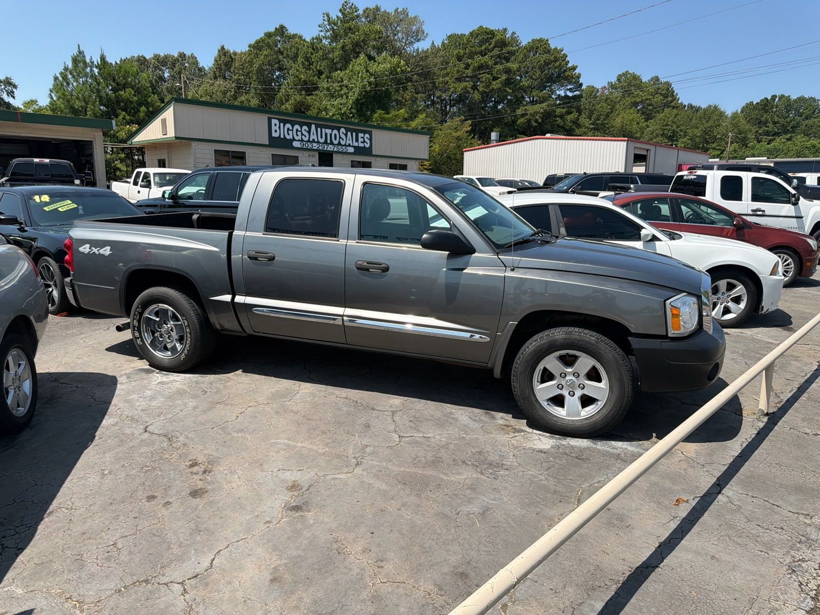 Gray pickup truck parked in a used car lot on a sunny day