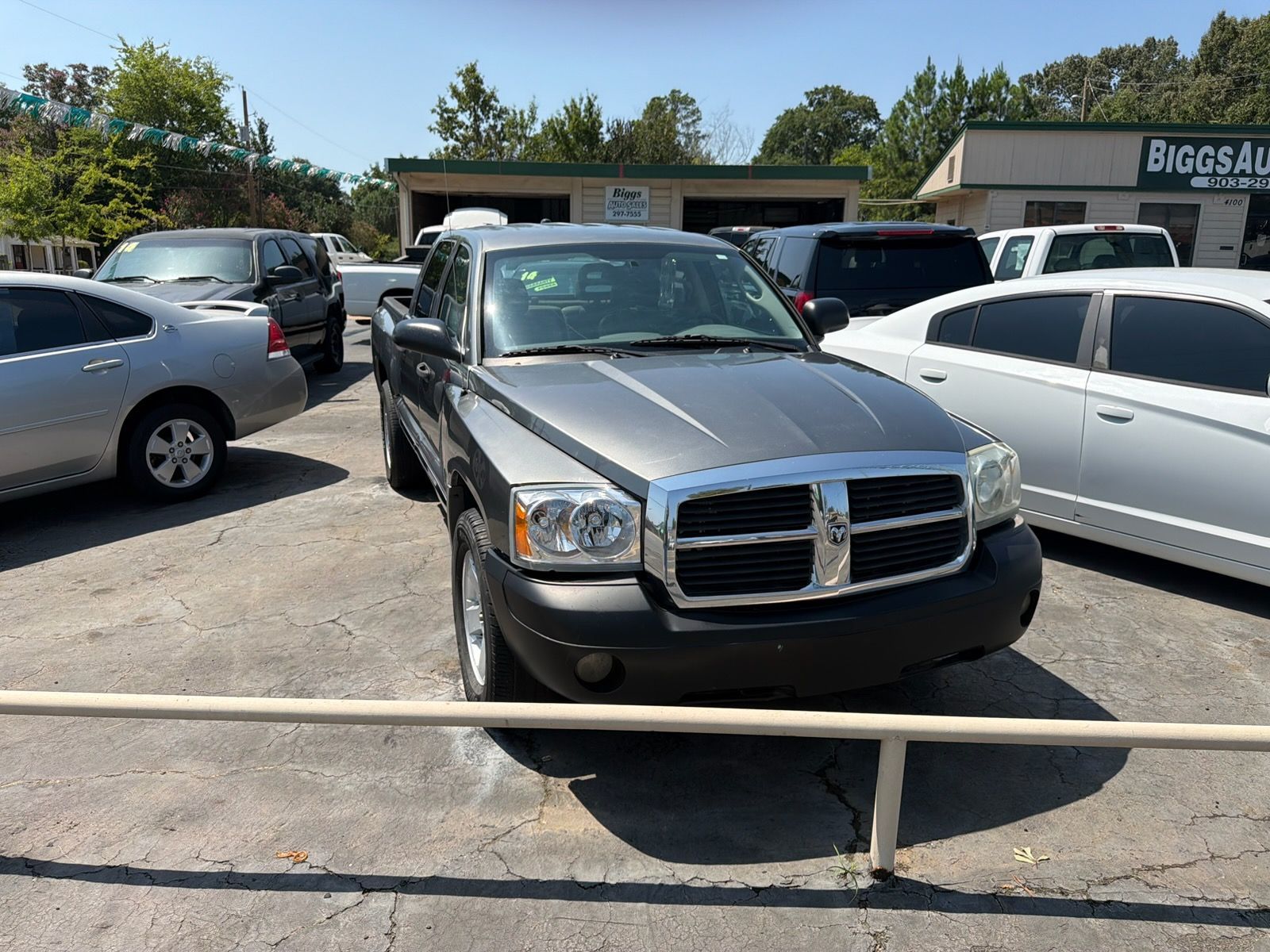 Black Dodge SUV parked in a lot between silver and white cars, with a building in the background