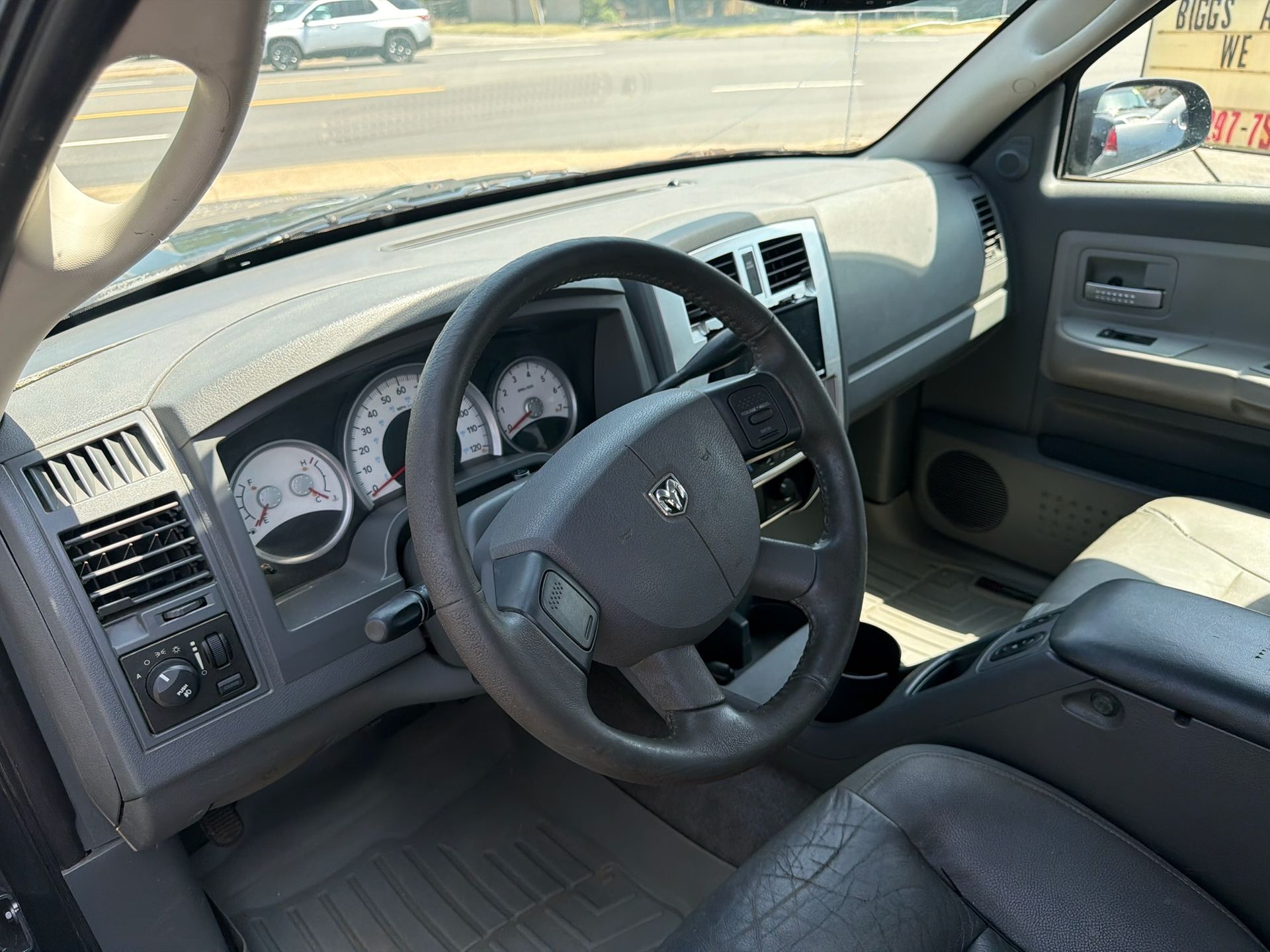 Car interior with black dashboard, steering wheel, and gray seats, viewed from the driver’s side.