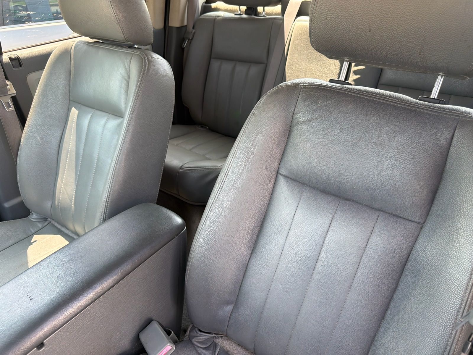 Interior of a car with gray leather seats and a visible back row.