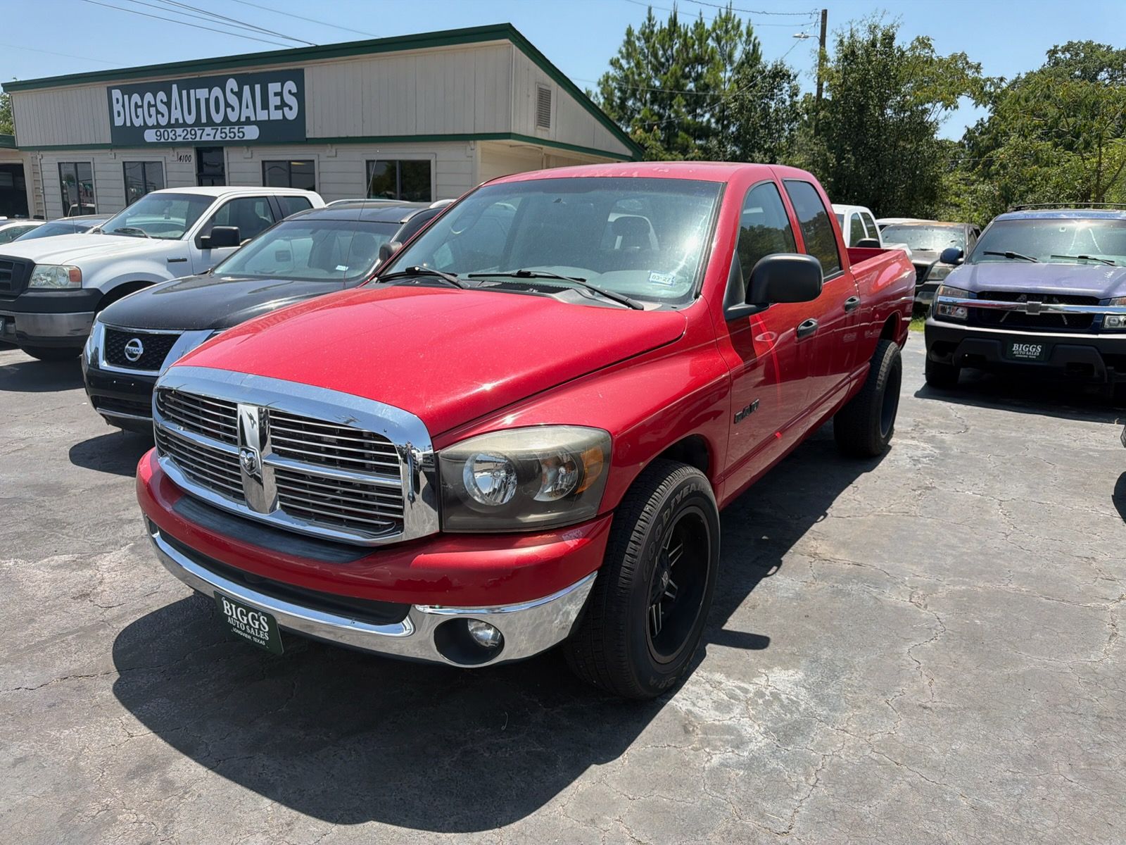 Red pickup truck parked at a car lot with other vehicles in the background
