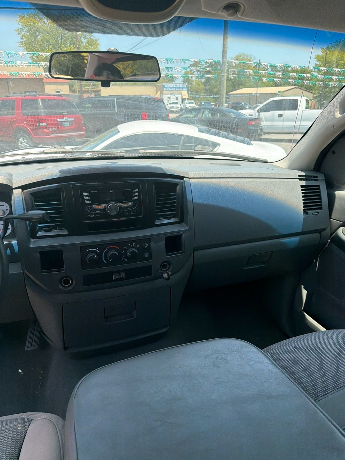 View from inside a truck cab, showing the dashboard, windshield, and parked cars outside.