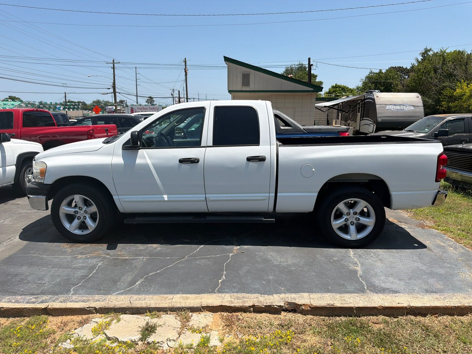 White crew cab pickup truck parked on a driveway under a sunny blue sky