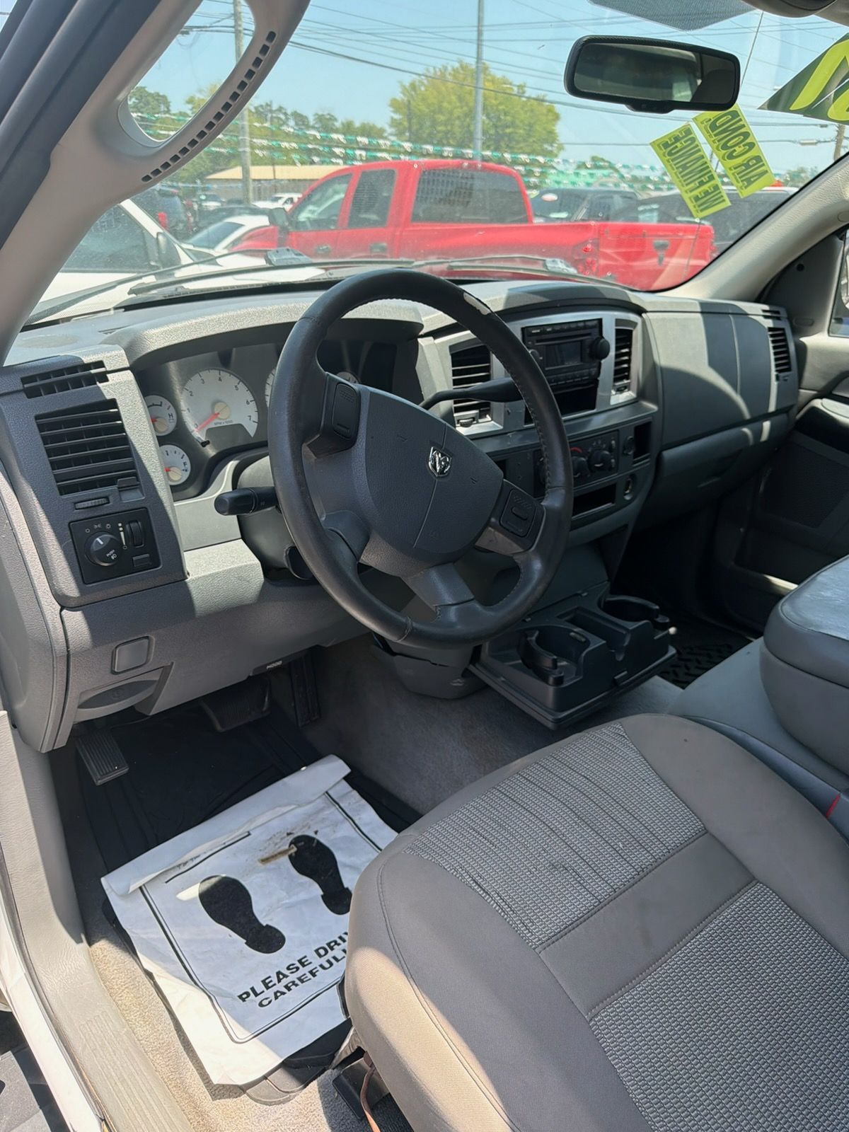 Truck interior with gray seats and steering wheel, viewed from the driver’s side, parked outdoors