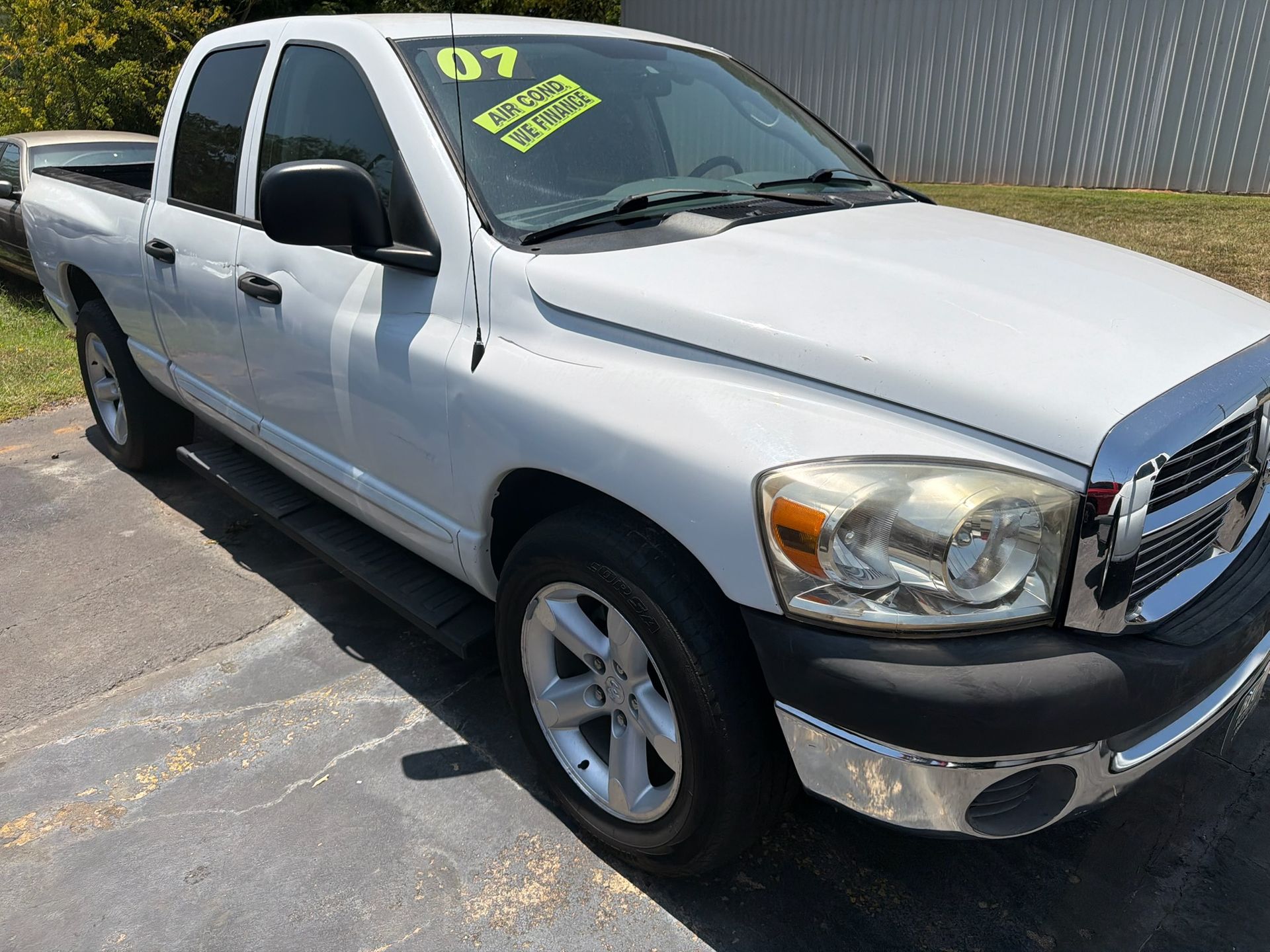 White pickup truck parked on pavement, front-left view, with yellow sale sticker on windshield