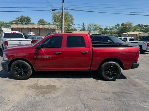 Red pickup truck with black wheels parked in a lot under a sunny sky