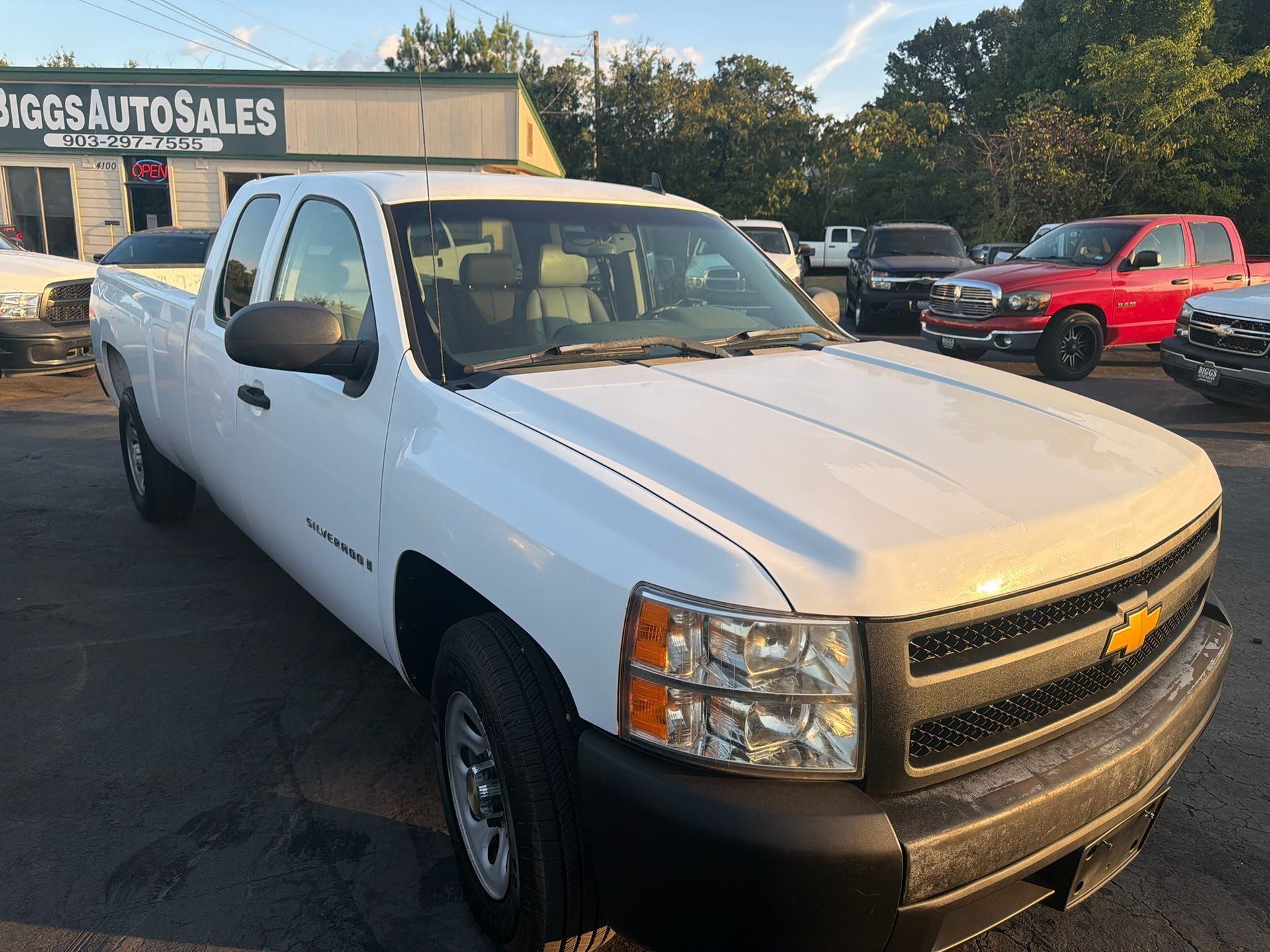 White Chevrolet pickup truck parked at a used car lot with other vehicles in the background