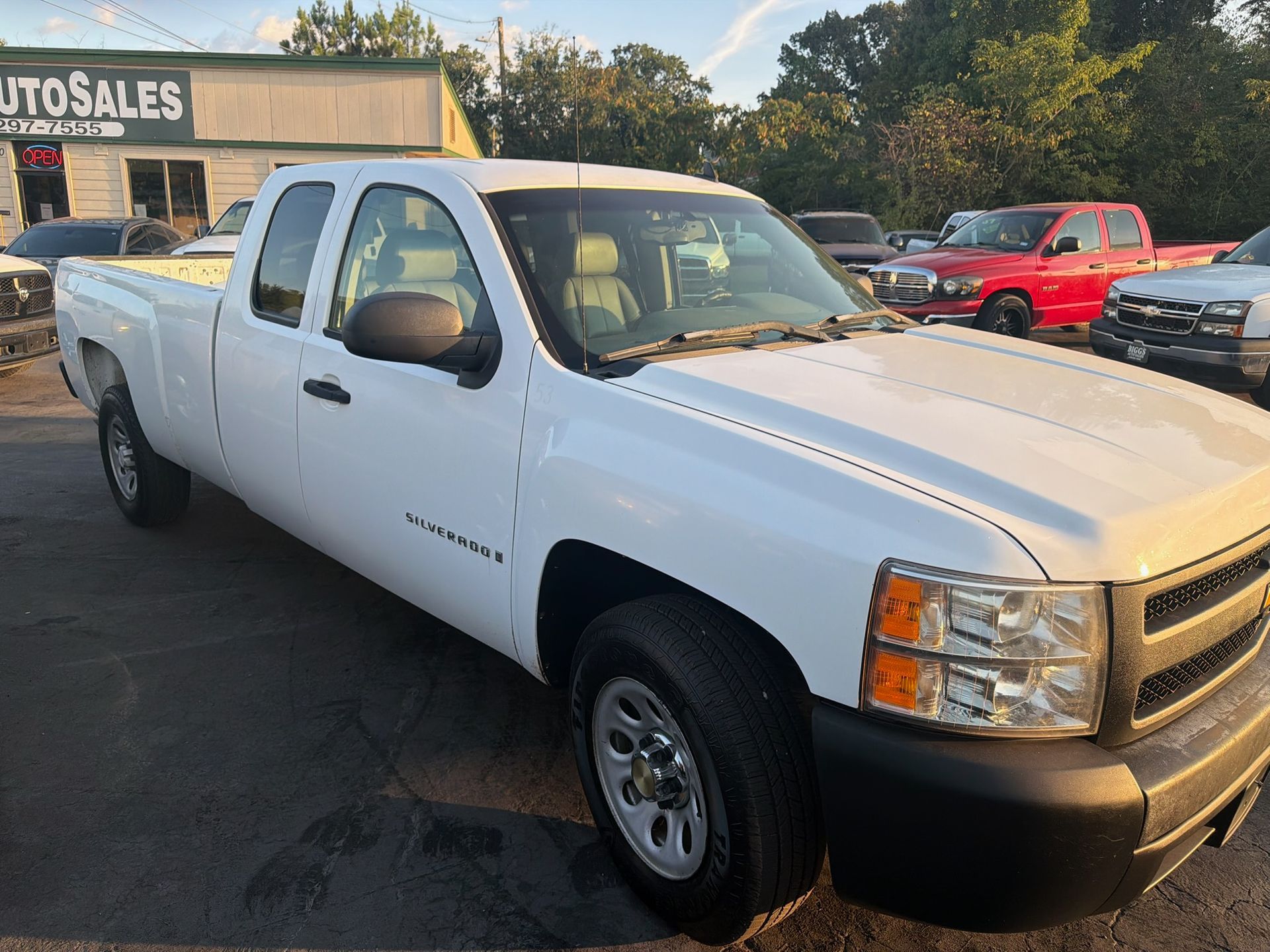 White extended-cab pickup truck parked at a car lot, viewed from the front-left side.