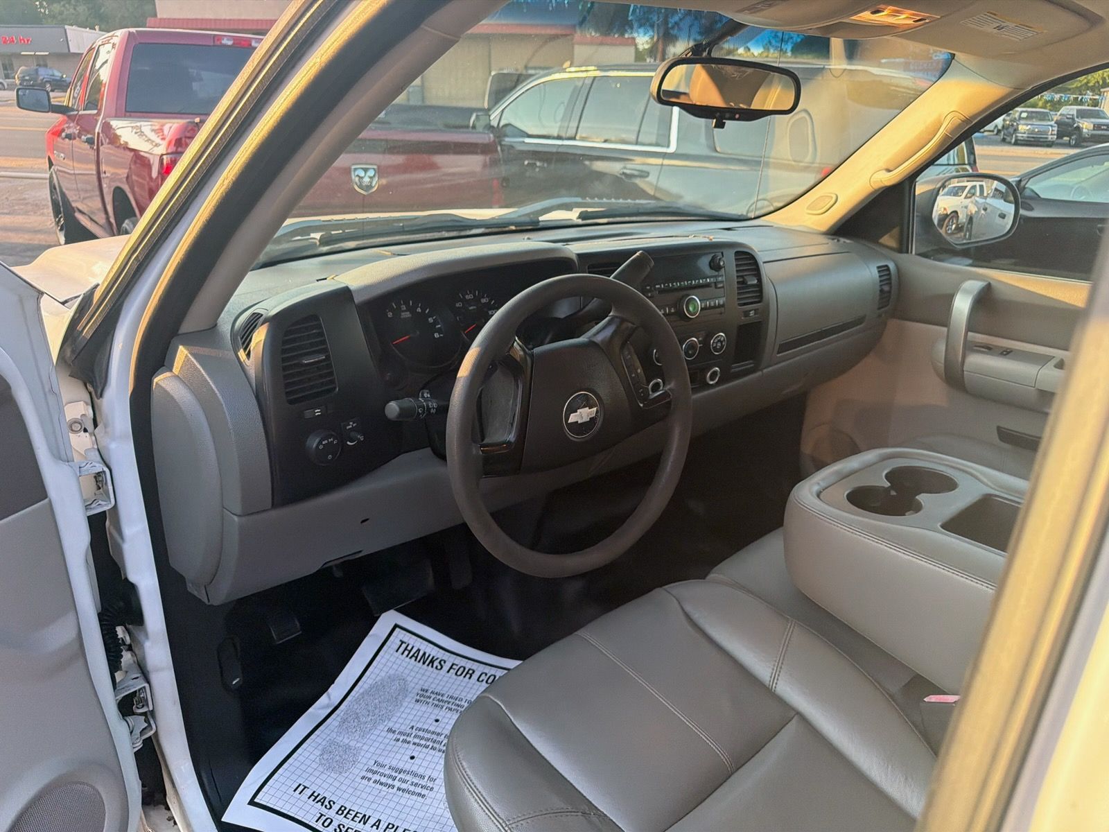 Open truck interior with tan seats, black steering wheel, and center console with cup holders