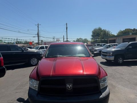 Red Dodge truck parked in a lot, front view with other vehicles nearby.