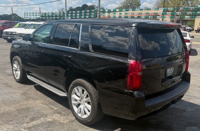 Black SUV parked in a lot, rear three-quarter view with other cars and a fence in the background