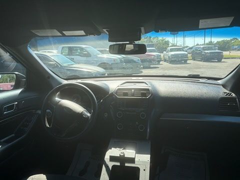 View from inside a car showing a parking lot through the windshield, with dashboard and steering wheel in foreground