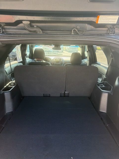 Car interior with rear seats folded flat, creating a cargo area with a black floor mat.