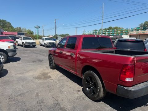 Red pickup truck parked in a lot with several vehicles and stacks of green crates in the background
