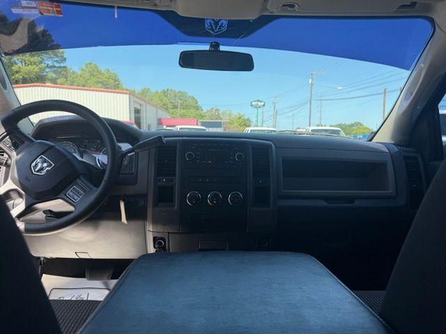 View from the driver’s seat inside a parked car, showing the steering wheel, dashboard, and front windshield.