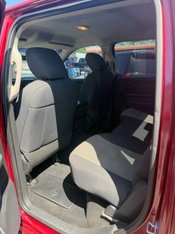 Open rear passenger door showing a gray car seat and empty back seat inside a red vehicle.